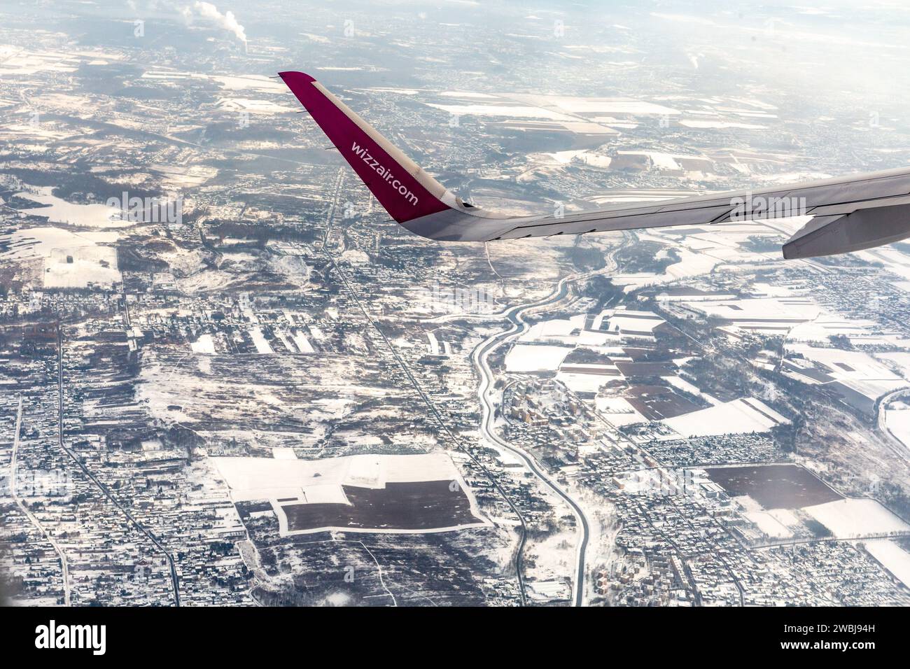 Krakow, Poland, 11 January 2024. Arial view from a plane of Wizzair plane wing and air pollution haze over Krakow and its suburbs as temperatures dropped well below 0 Celsius over last days. The air pollution was declared very unhealthy and PM2.5, and PM10 concentration was much higher than the WHO annual air quality guidelines. The pollution is a combination of lack of wind and low temperatures which forced the city and its inhabitants to heat their homes more. Stock Photo