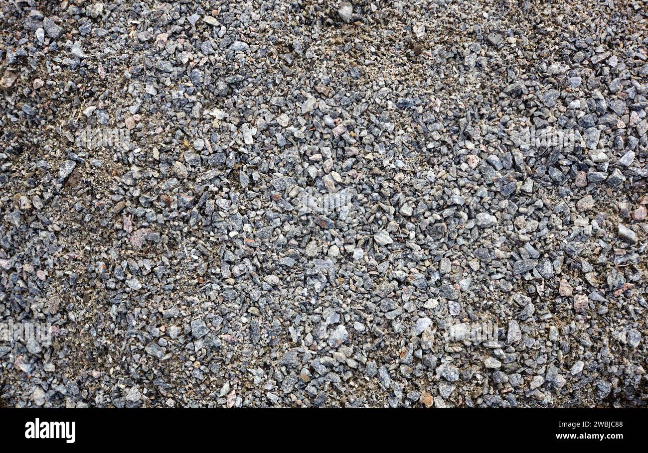 Grey ground stone rubble road background. Natural gray granite chippings, macadam, rubble or crushed stones texture, top view Stock Photo