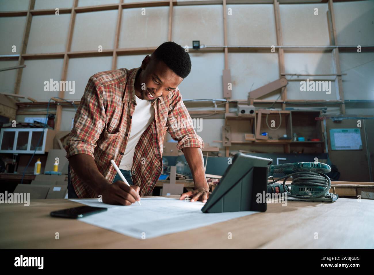 Happy African male designing carpentry project with tablet open Stock ...
