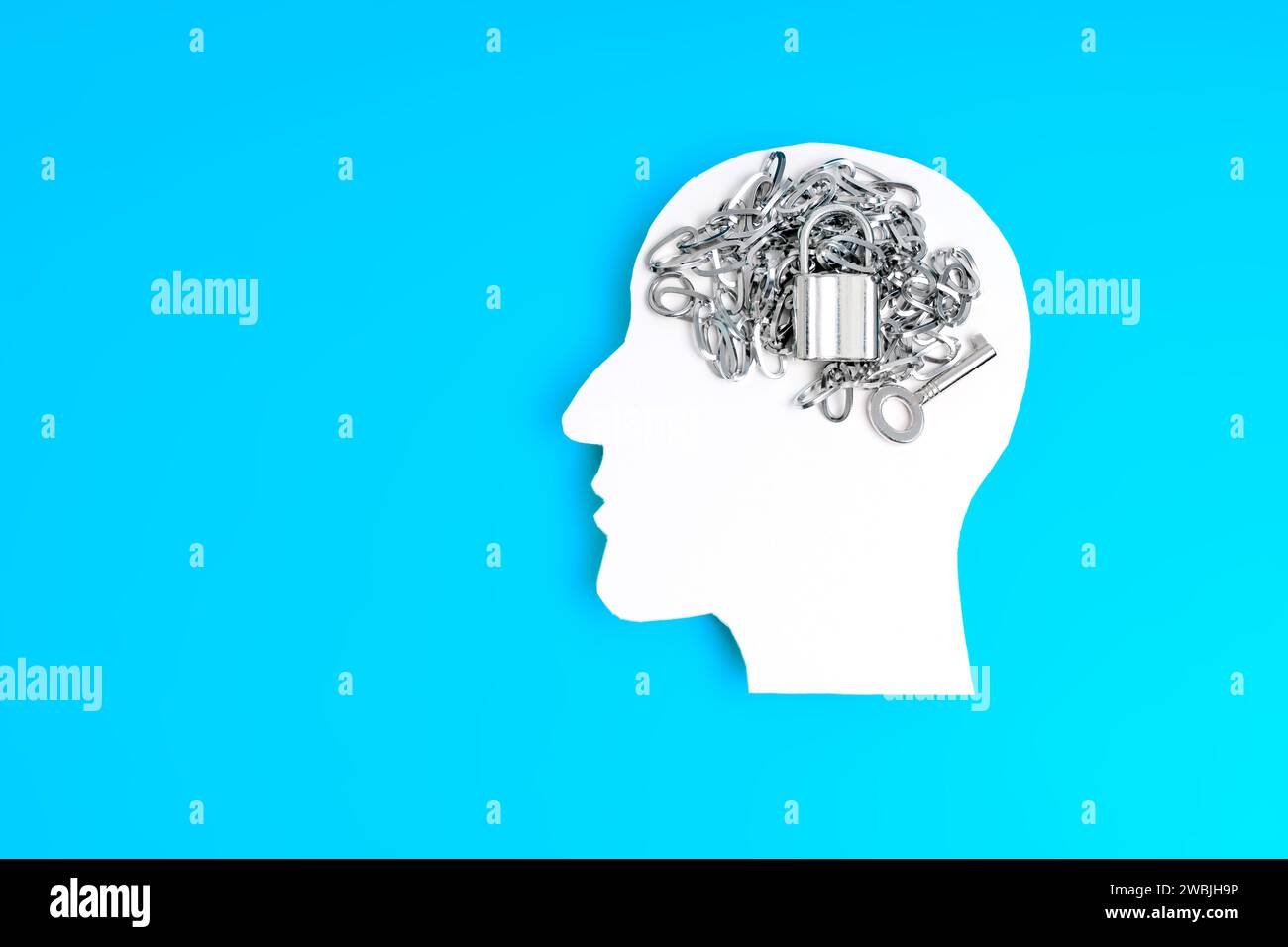 White paper silhouette of a male head in profile isolated on blue with a chain, lock, and key, suggesting the pursuit of unlocking one's potential. Stock Photo