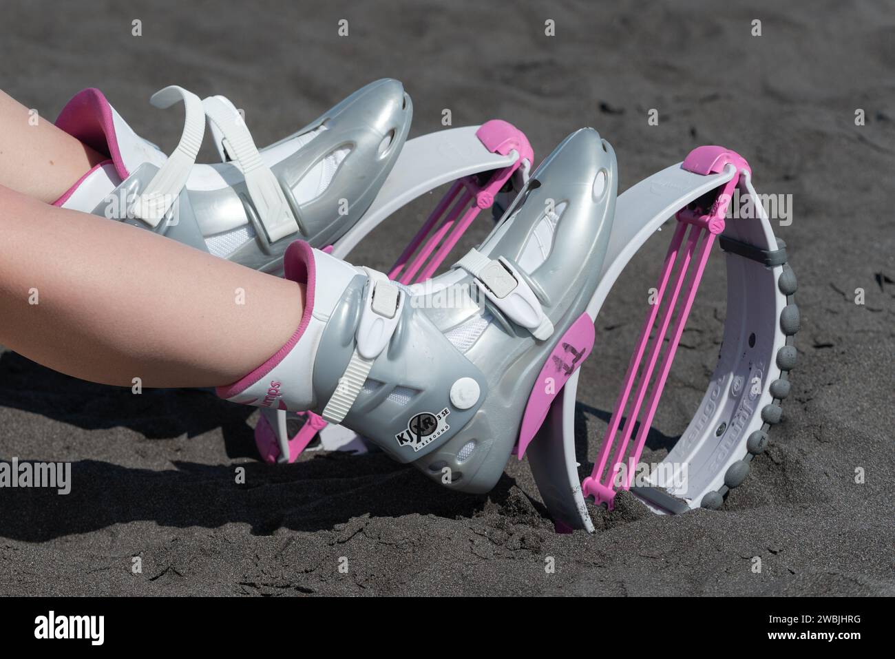 Woman with kangoo jumping boots sitting in workout park Stock