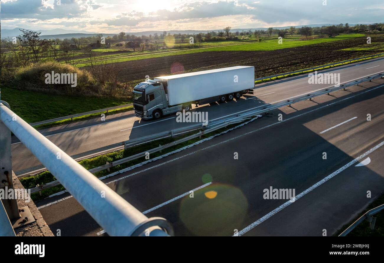 Big industrial semi truck for long haul delivery commercial cargo with semi trailer advancing along the highway Stock Photo
