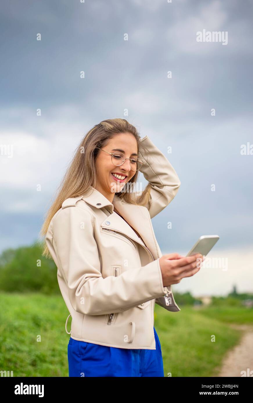 lachende junge Frau mit smartphone steht auf einer Weise *** laughing young woman with smartphone stands in a way Stock Photo