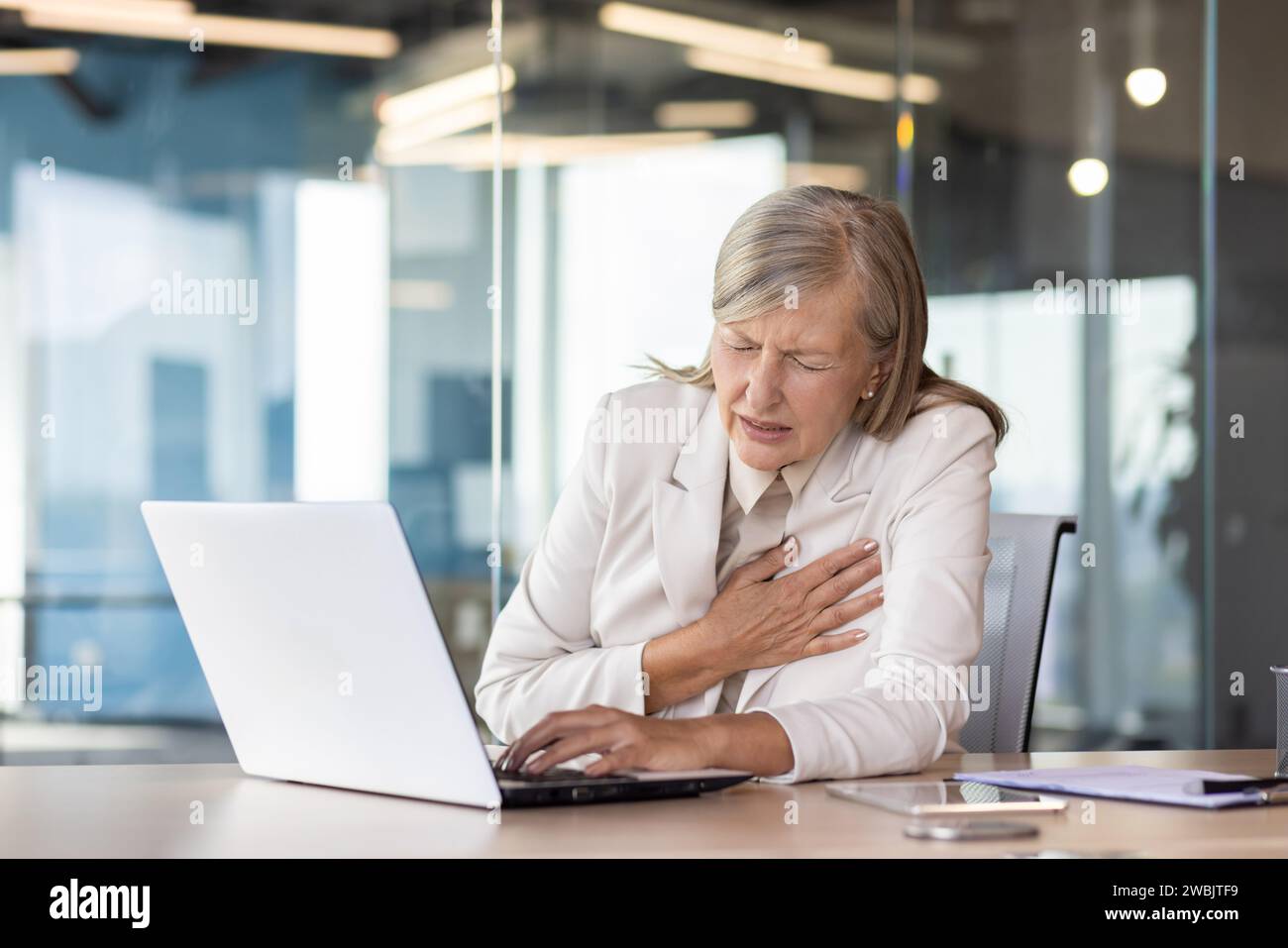 Heart attack chest pain, senior mature businesswoman in business suit ...