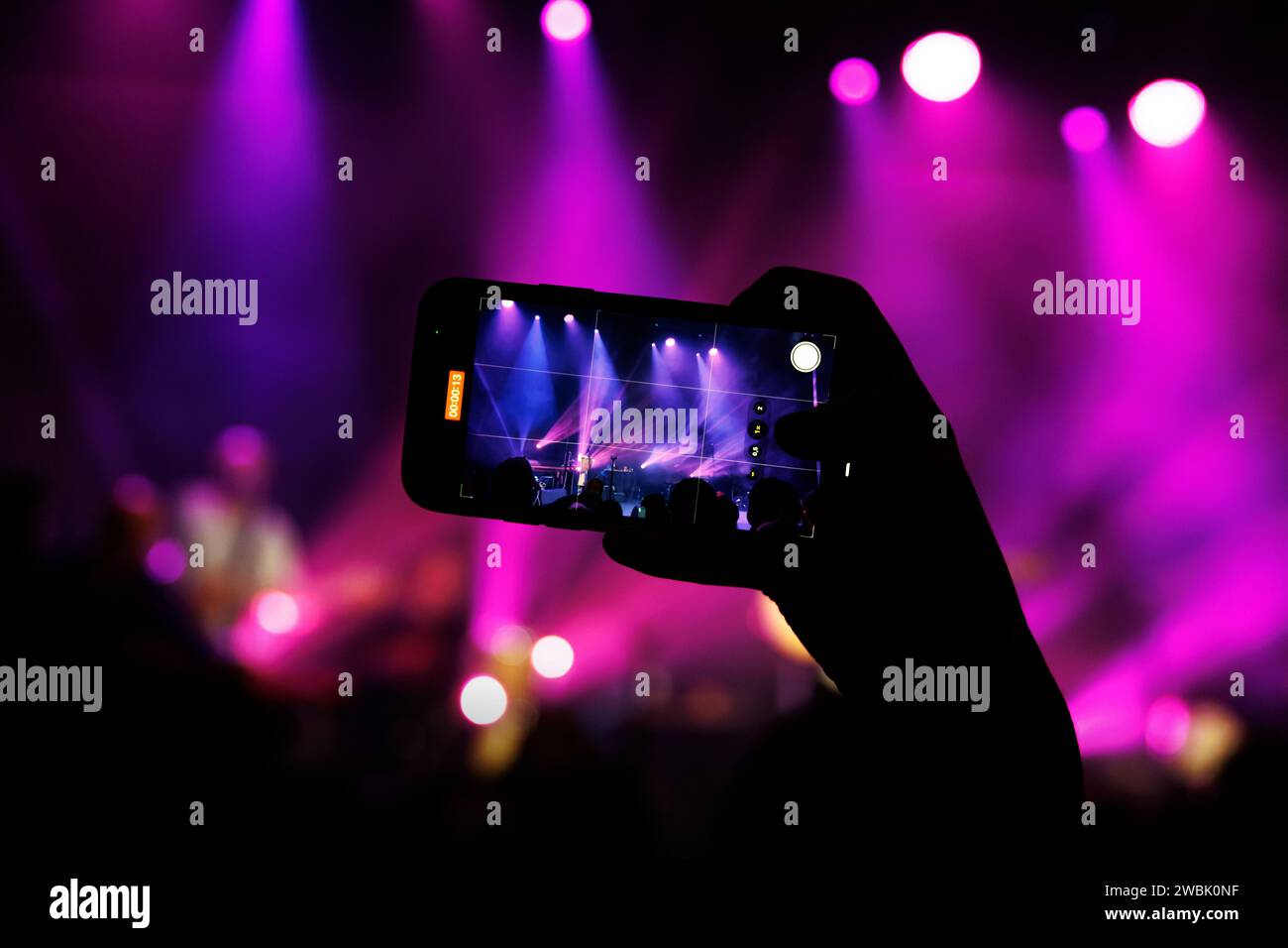 A concert-goer captures the live performance of a band on their phone ...