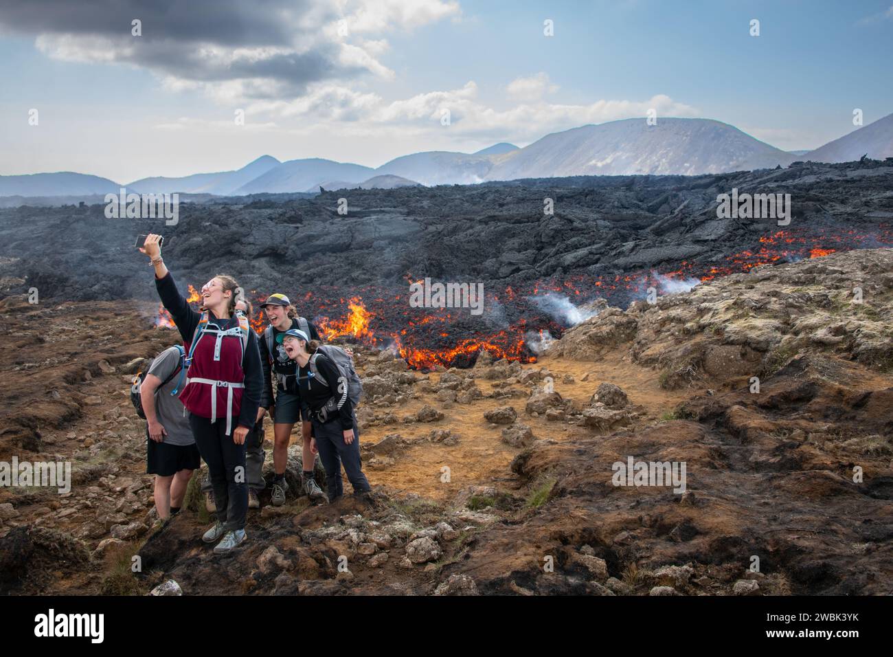 A group of tourists taking a selfie in from of a lava eruption in Iceland Stock Photo