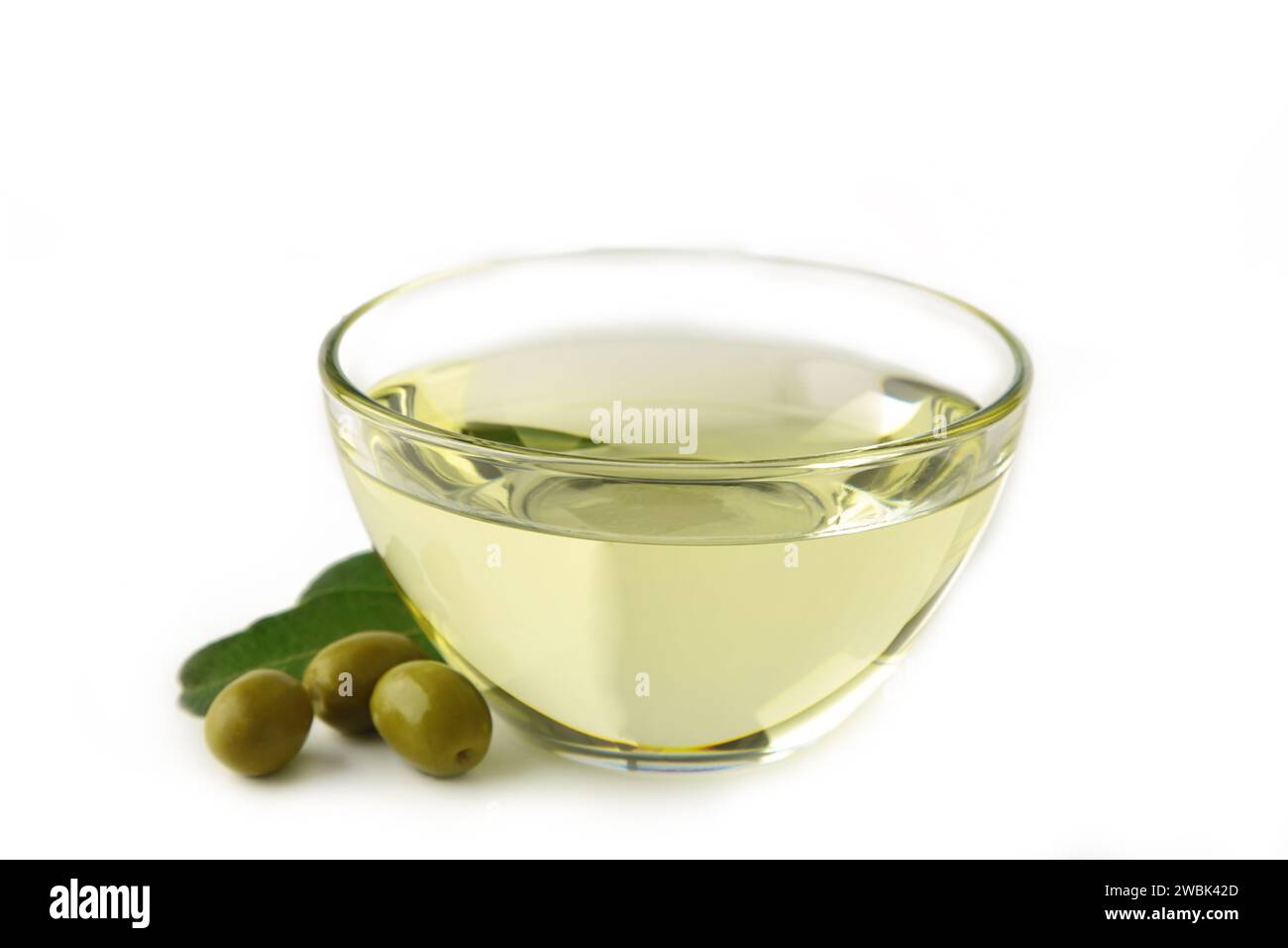 Bowl of fresh extra virgin olive oil and green olives with leaves isolated on white background. Stock Photo