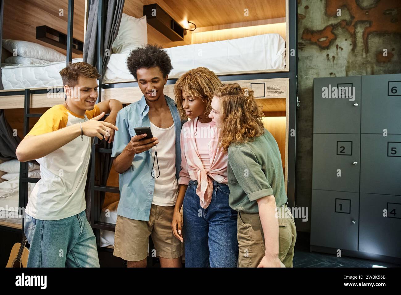 happy african american student using mobile phone near multiethnic friends in youth hostel Stock Photo