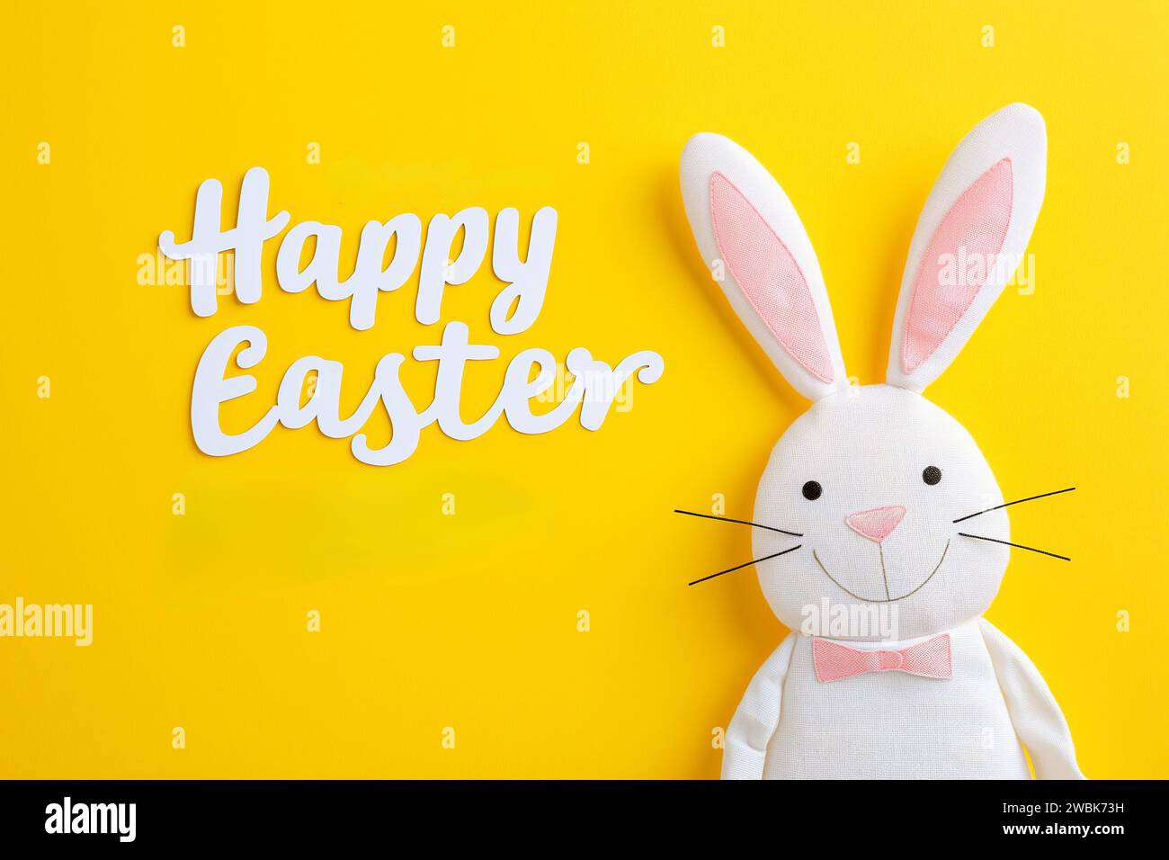 Happy easter, Happy Easter Greeting with Cartoon Bunny on Bright Yellow Background and Playful White Cursive Font Stock Photo