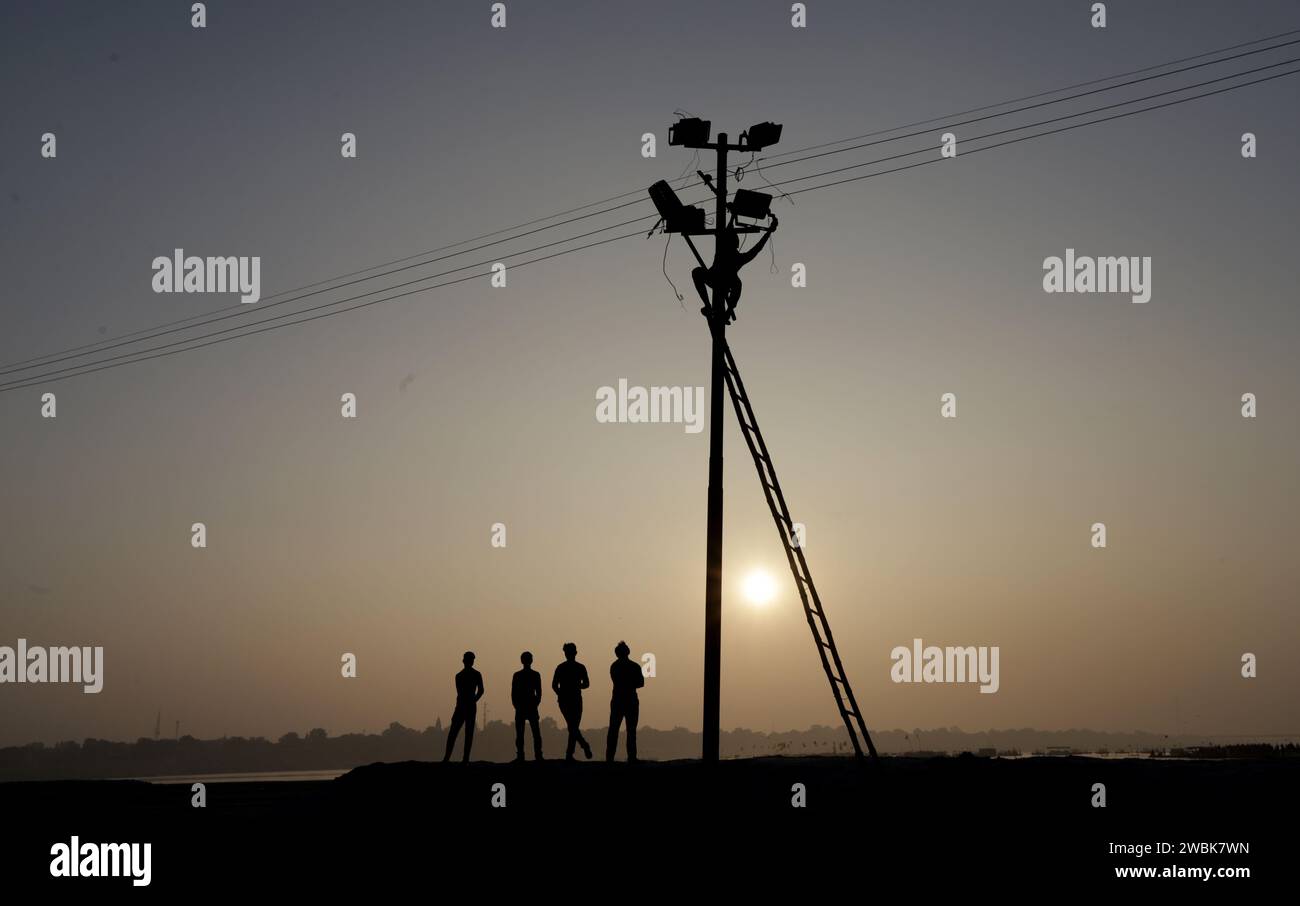 Prayagraj, India. 11 January 2024, Indian labourers fix electric cables and flood lights  at the banak of river Ganges during the prepraion for the upcoming one month long Magh Mela 2024 , in Prayagraj, India.  Credit: Anil Shakya/Alamy Live News Stock Photo
