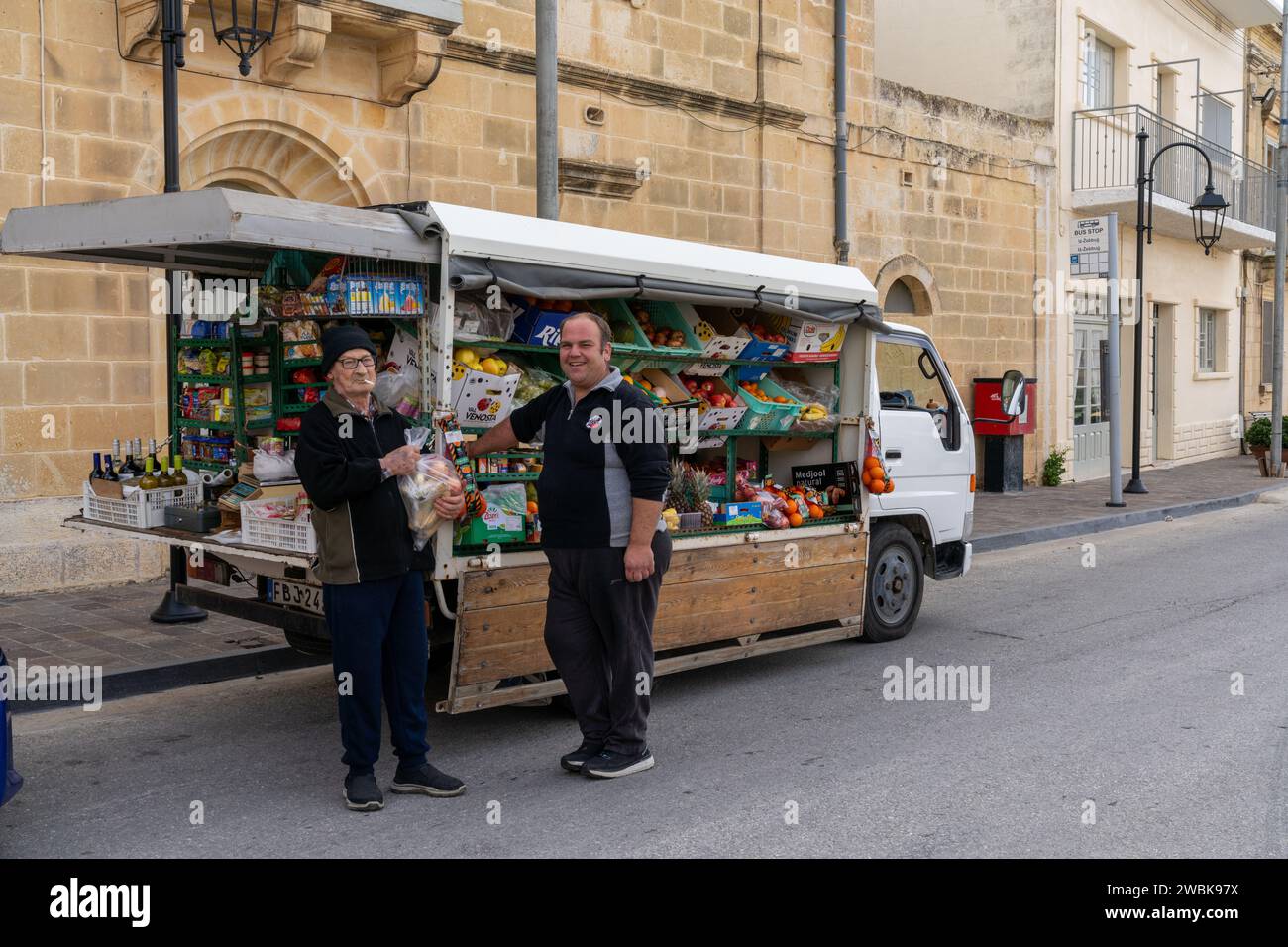 Zebbug, Malta - 19 December, 2023: mobile greengrocer and senior citizen customer in a remote village on Gozo Island in Malta Stock Photo