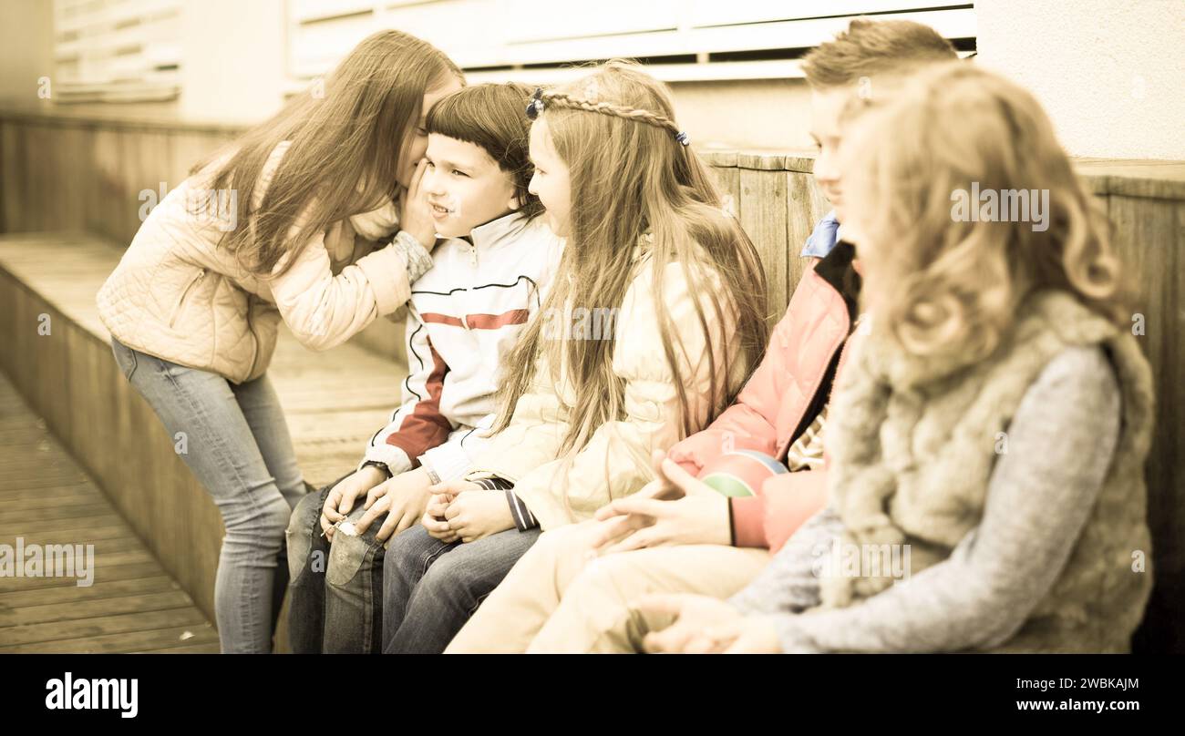 Children on a bench playing Chinese whispers Stock Photo