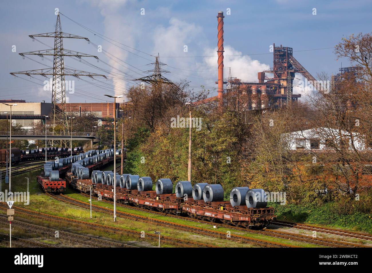 Duisburg, Ruhr area, North Rhine-Westphalia, Germany - ThyssenKrupp Steel Europe, here blast furnace Schwelgern 2 in Duisburg-Marxloh, in front steel coils from the hot strip mill cooling on freight cars in the outdoor area. Stock Photo