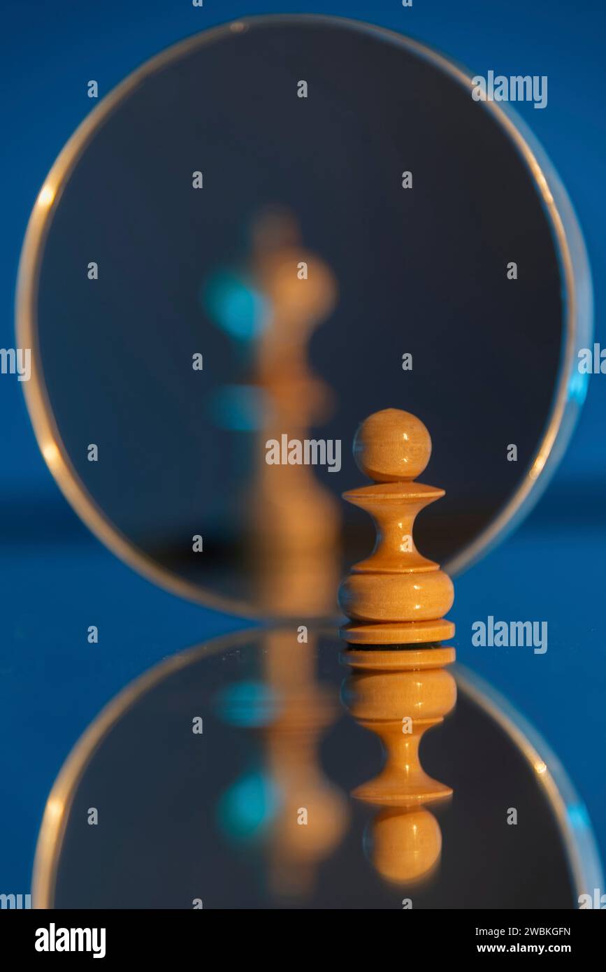 Chess pieces, pawn, behind it king blurred in the mirror Stock Photo