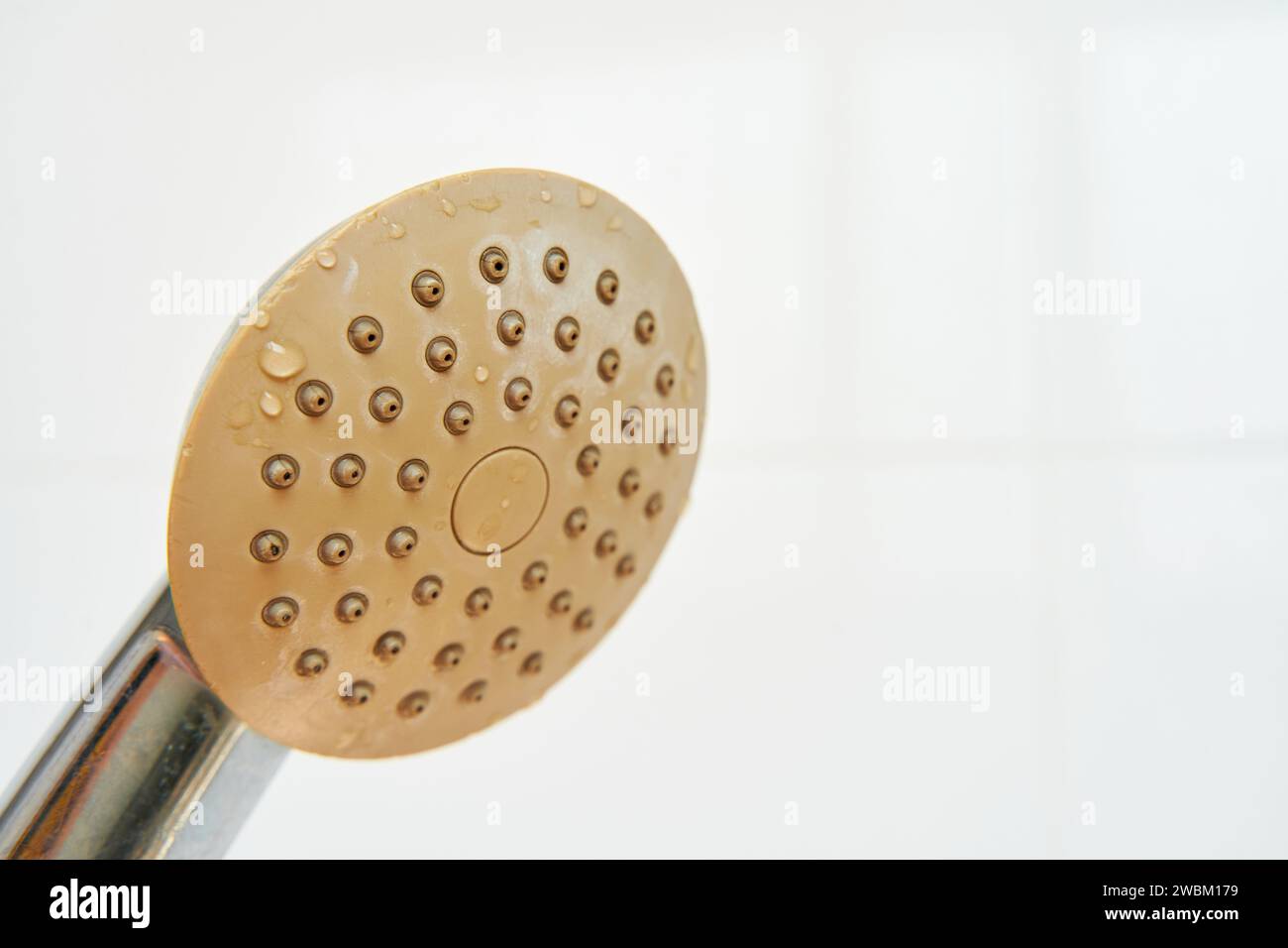 Dirty corroded limescale calcified old shower head hanging from a stand