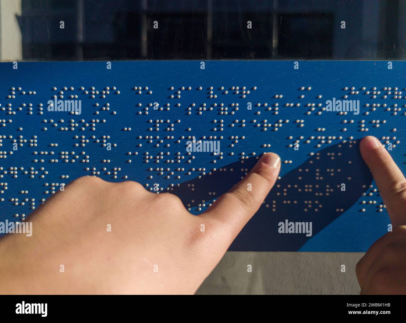 Child hands reading text caption in braille language at bus stop glass. Accesible transports concept Stock Photo