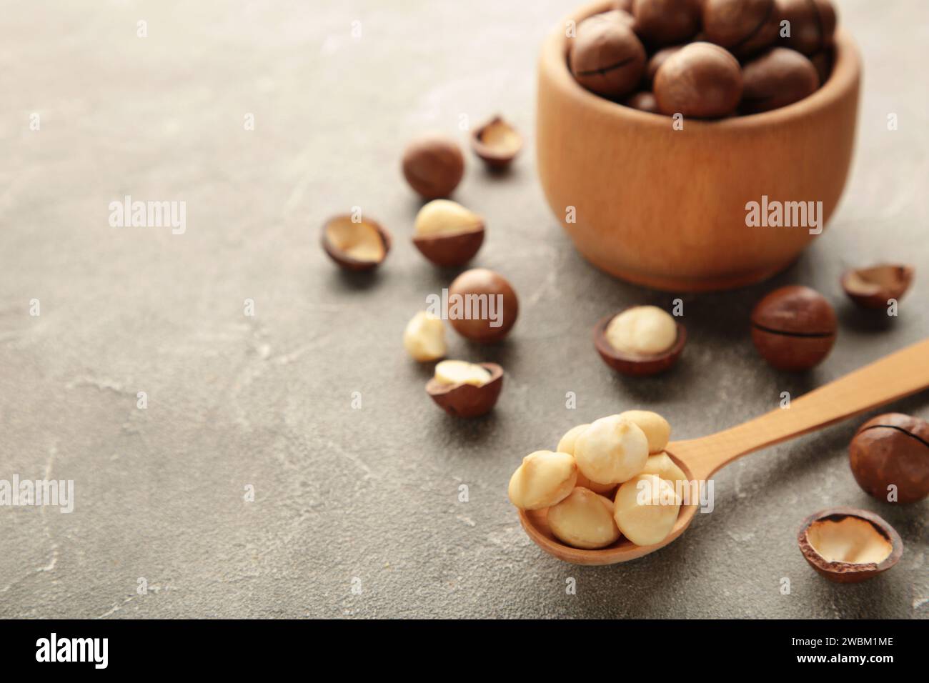 Macadamia in wooden spoon on grey background. Favorite for snack and very delicious.Have a lot of unsaturated fatty acid. Healthy food concept. Top vi Stock Photo