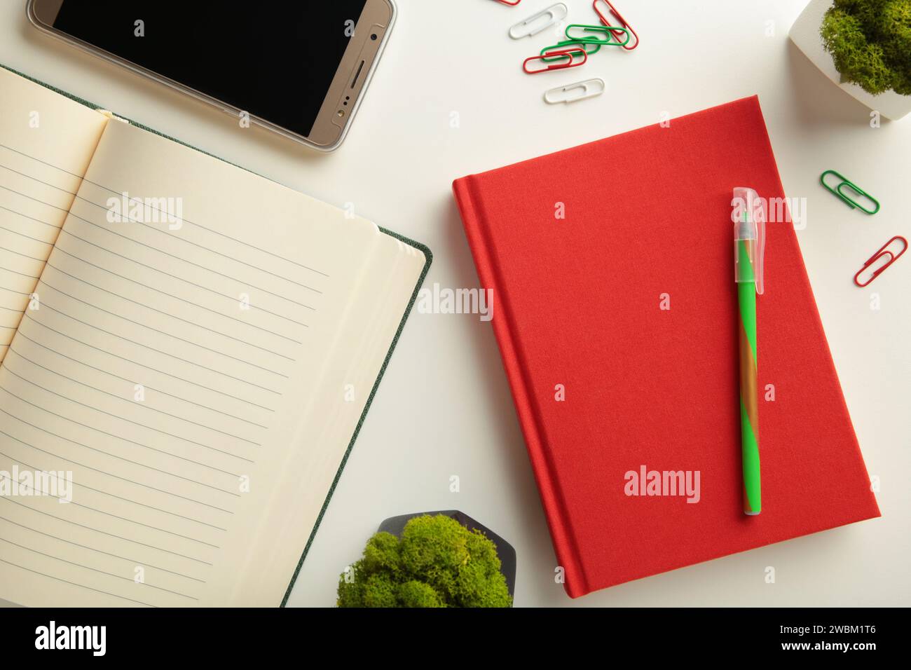 Red notebook with smartphone on grey background. Top view Stock Photo