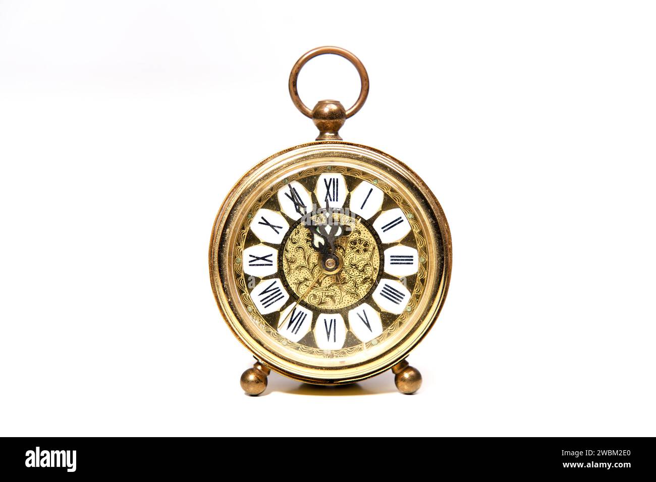 an old golden analog alarm clock with mechanical movement isolated on a