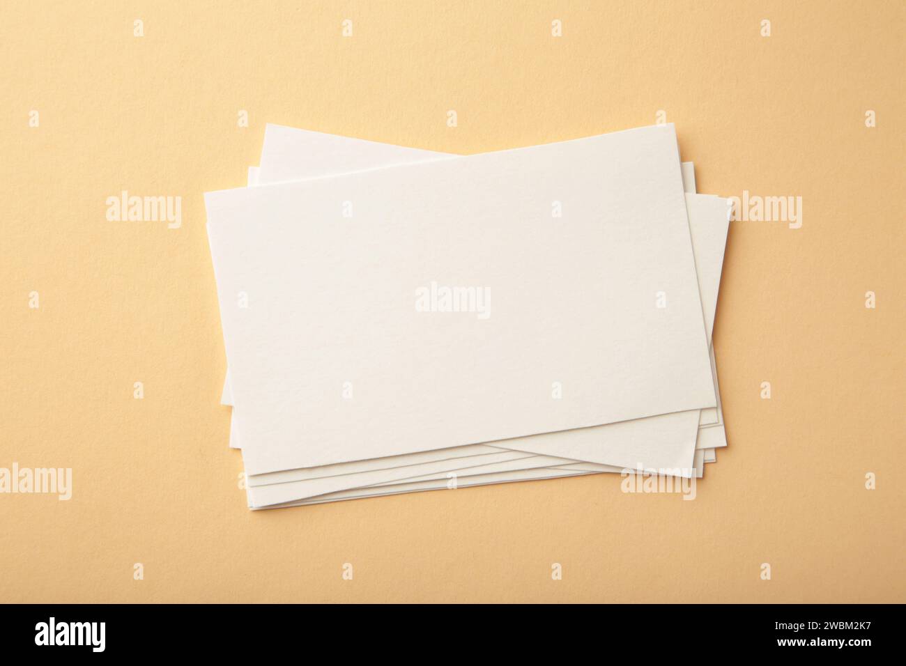 Blank white business cards on beige paper background. Mockup for branding identity. Template for graphic designers portfolios. Stock Photo