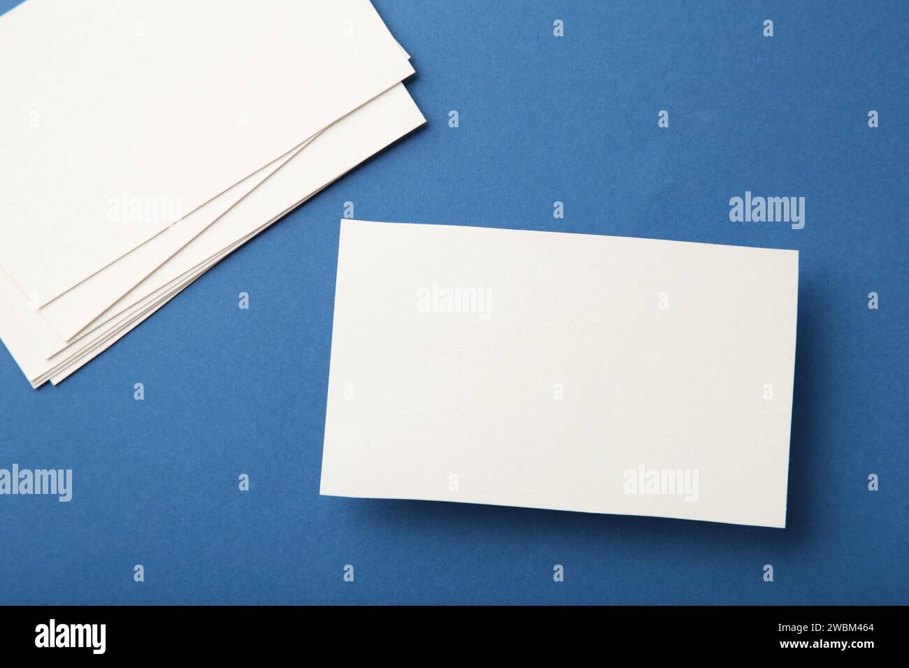Blank white business cards on blue paper background. Mockup for branding identity. Template for graphic designers portfolios. Stock Photo