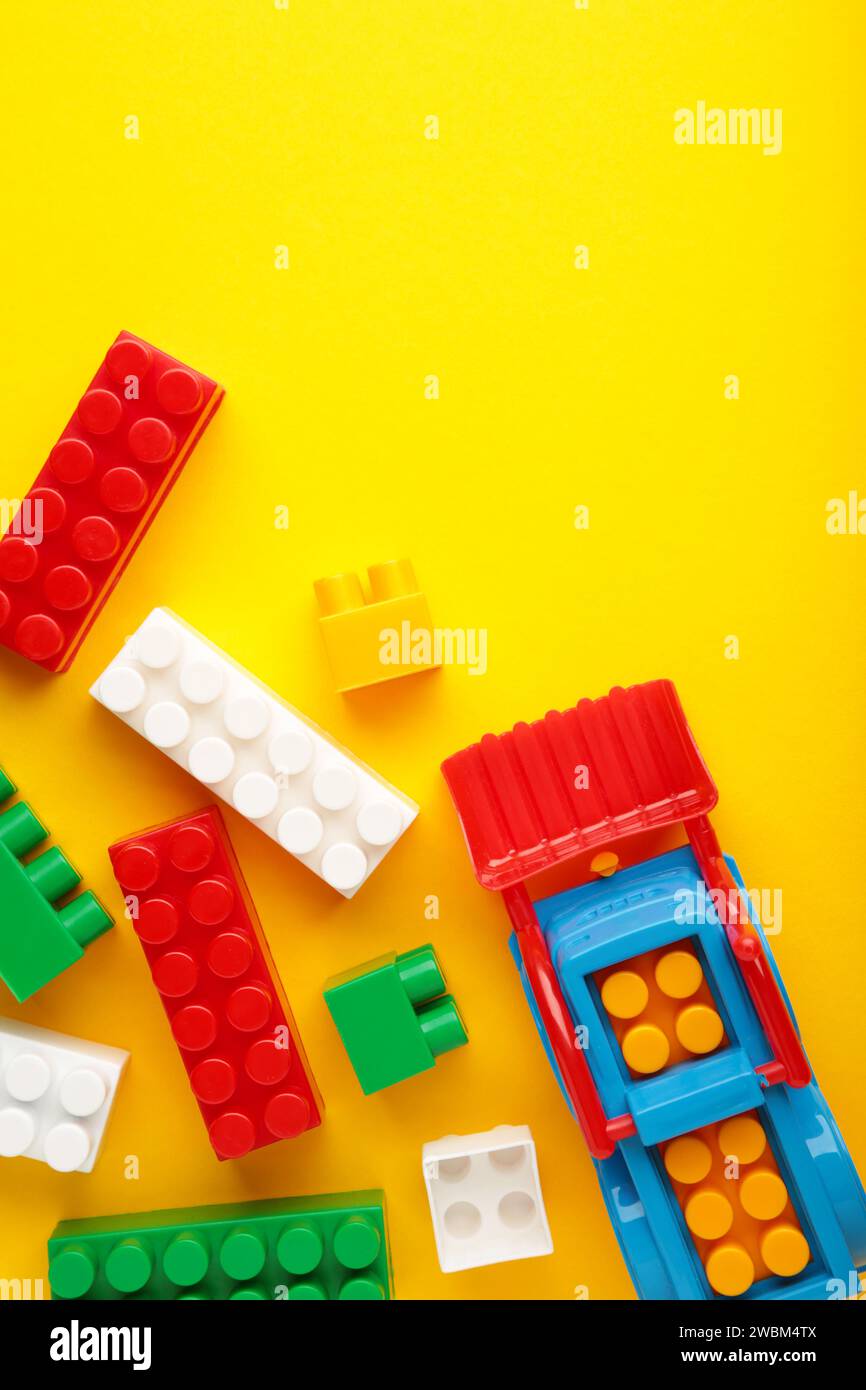 Multicolored blocks of the children's constructor lie on a yellow background. Stock Photo