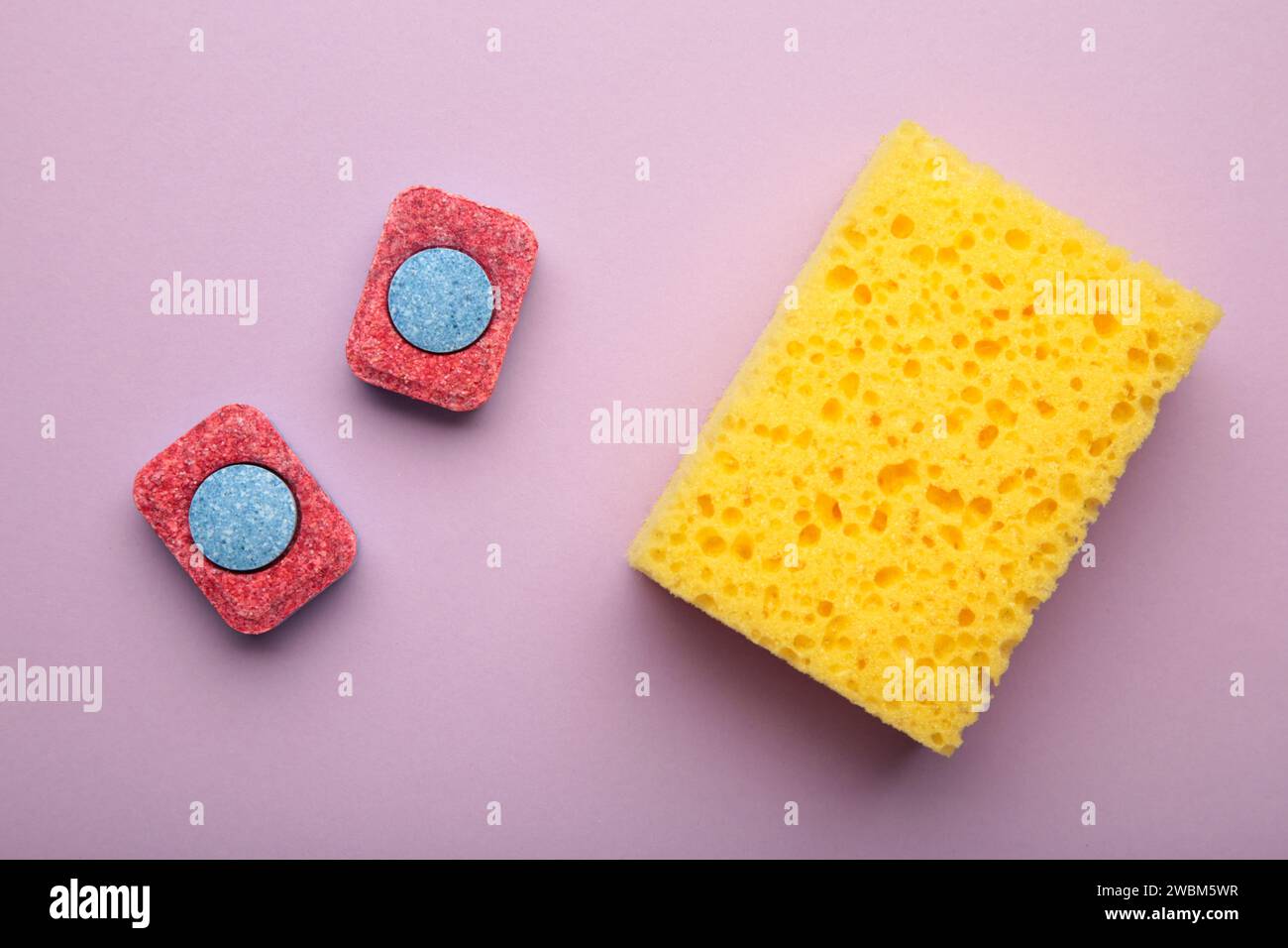 Dishwasher tablets on a dishwashing sponges on a purple background, dishwashing products. Top view Stock Photo