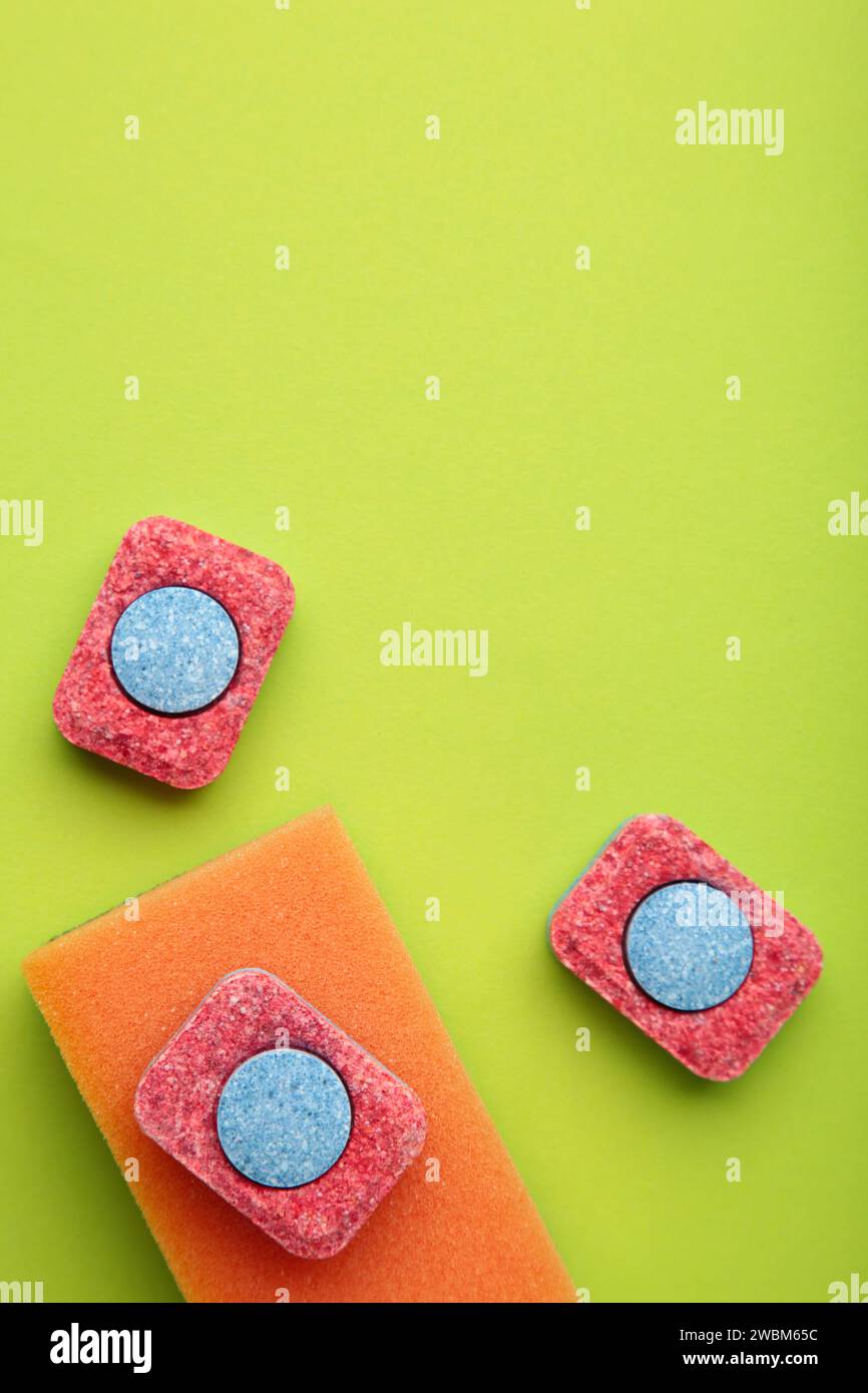 Dishwasher tablets on a dishwashing sponges on a green background, dishwashing products. Top view Stock Photo