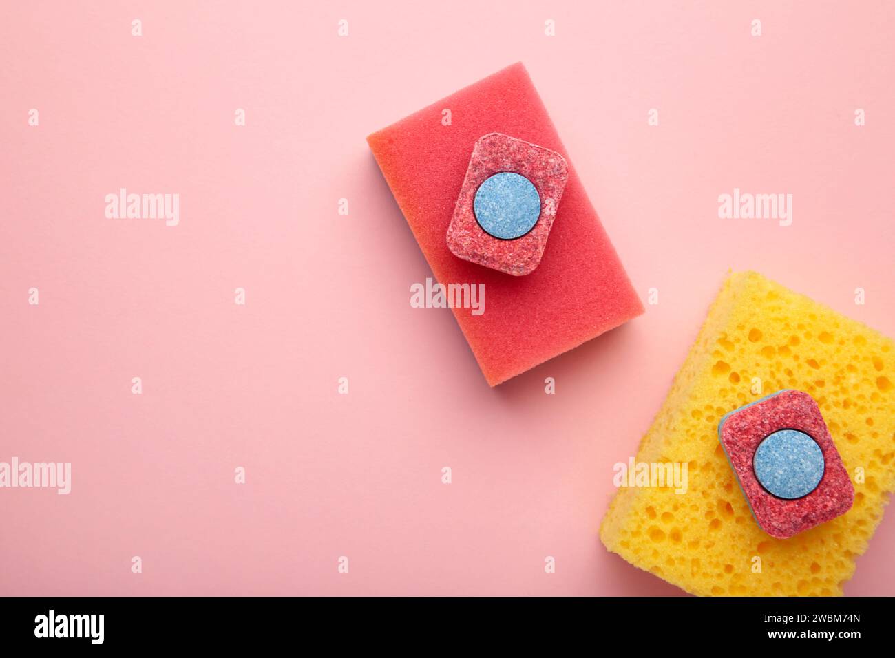 Dishwasher tablets on a dishwashing sponges on a pink background, dishwashing products. Top view Stock Photo