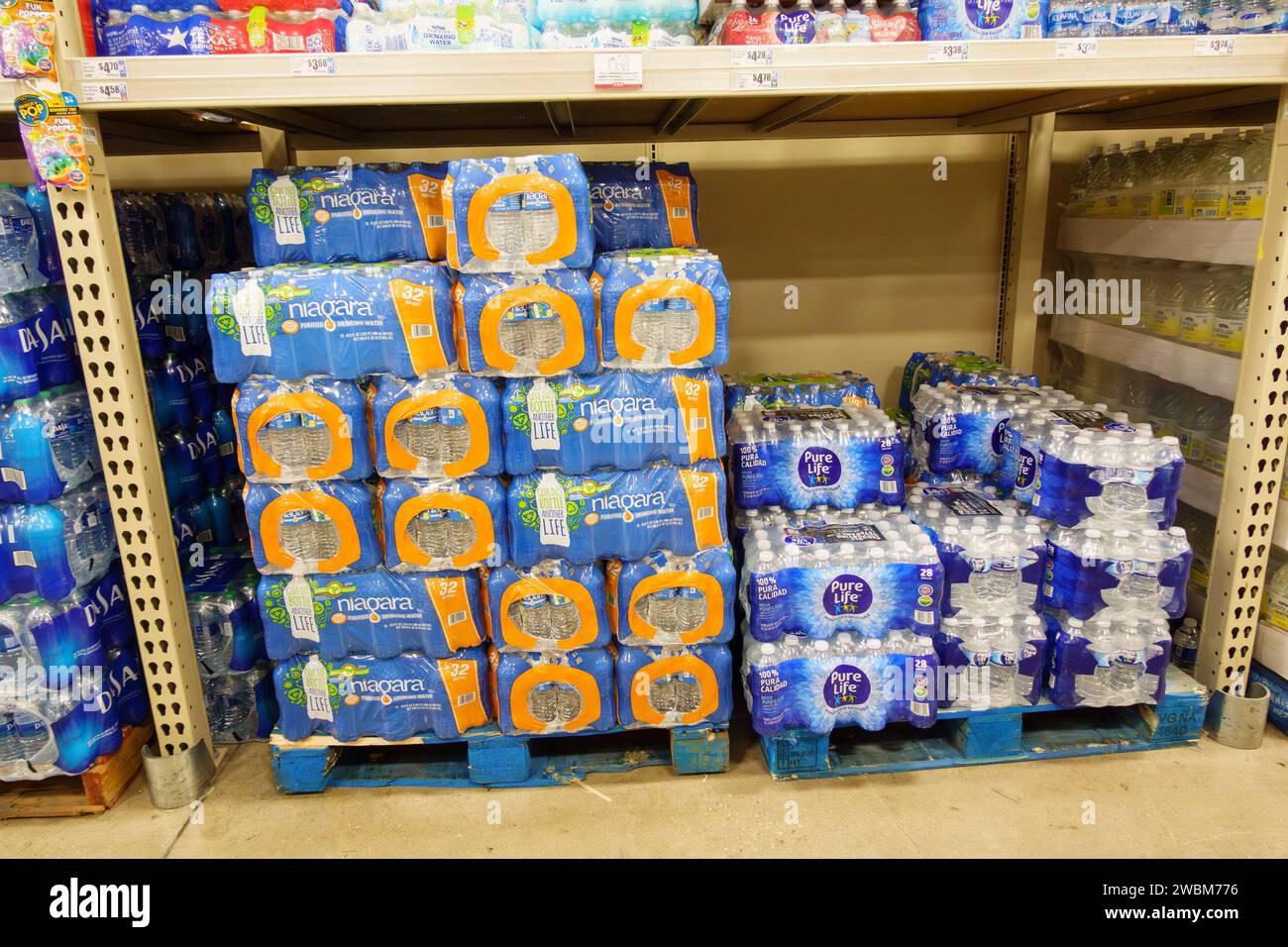 Bundles of bottled drinking water on pallets in supermarket grocery Stock Photo