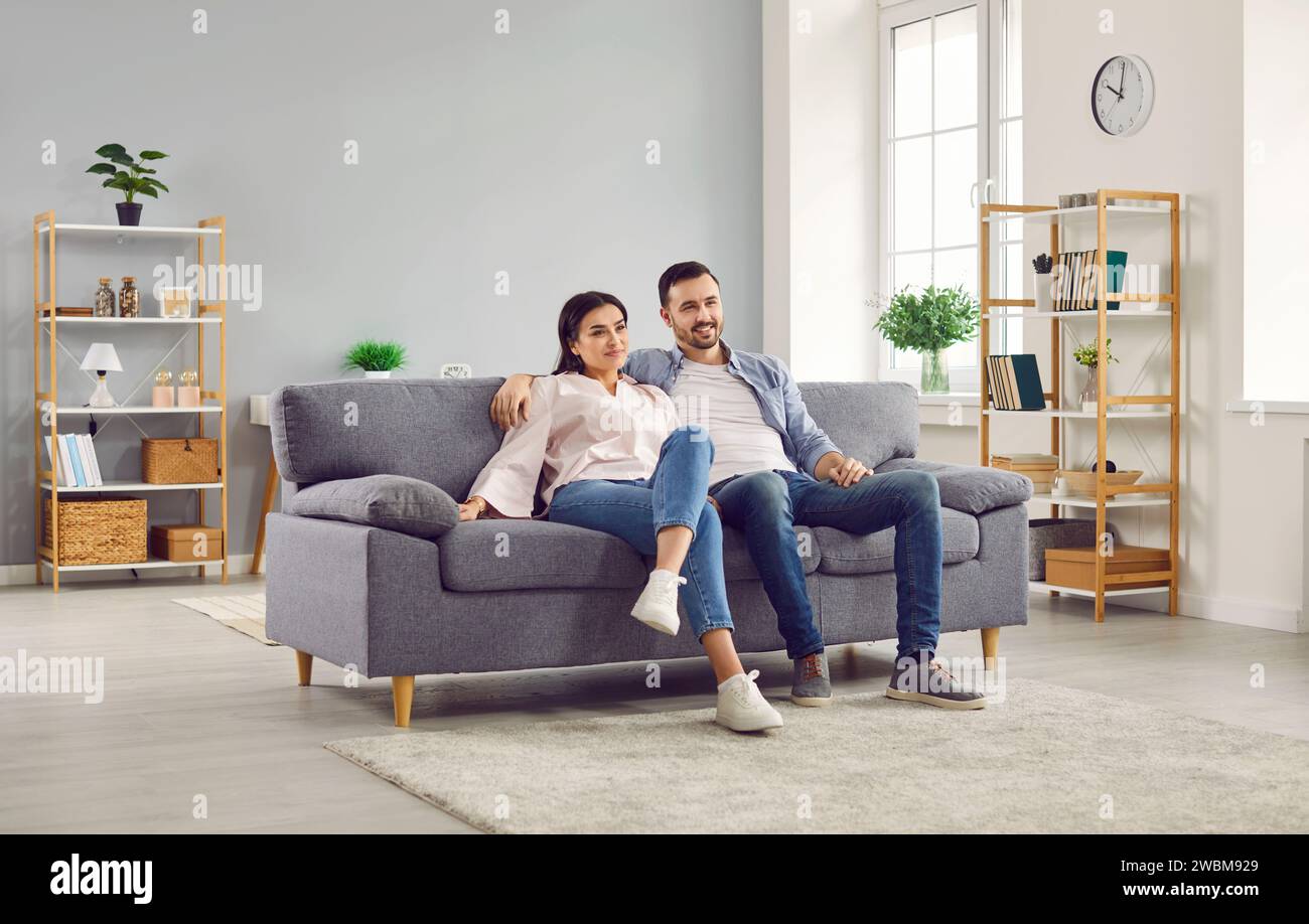 Couple watching TV together while sitting on couch in living room Stock Photo