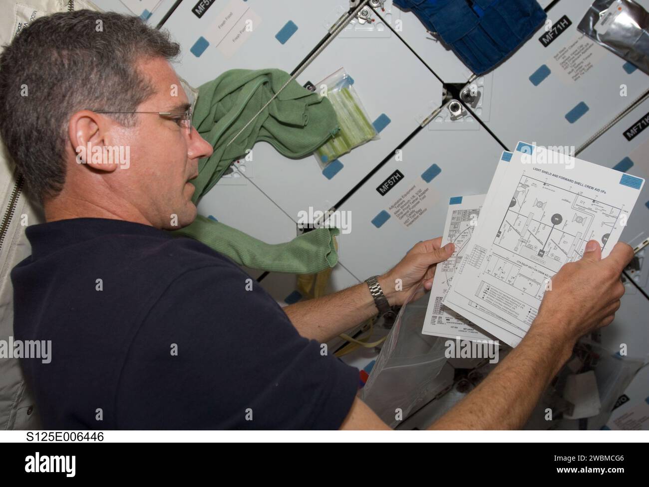 S125-E-006446 (12 May 2009) --- Astronaut Michael Good, STS-125 mission specialist, looks over charts on Atlantis? mid deck during his second day in space. The next several days prove to be very busy for the entire crew, as five spacewalks, two of which will have Good leaving the shirt sleeved environment of the shuttle to perform work on the Hubble Space Telescope, are in the offing. Stock Photo