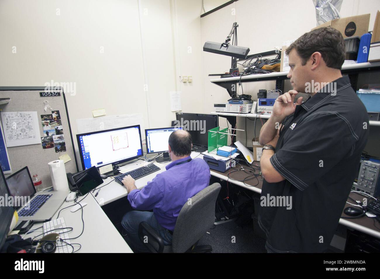 CAPE CANAVERAL, Fla. – Shaun Daly, right, and Robert Olsen test elements of a prototype of the StangSat at Kennedy Space Center before final assembly. The satellite is a small cube measuring 10 inches on all sides and will be launched on a rocket that will carry it on a suborbital mission in Mojave, Calif. Stock Photo