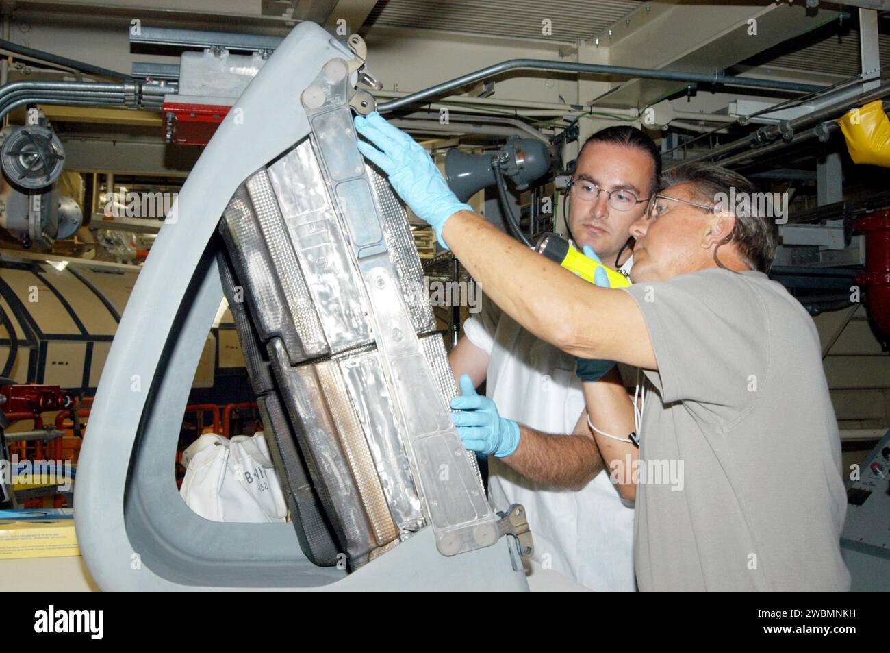 KENNEDY SPACE CENTER, FLA. -In the Orbiter Processing Facility, Matt Scott (left), with United Space Alliance, and Donald Wall (right), with NASA Quality Assurance, closely inspect the final Reinforced Carbon-Carbon (RCC) panel to be installed on orbiter Discovery’s left wing. The leading edges of each of an orbiter’s wings have 22 RCC panels. They are light gray and made entirely of carbon composite material, which protect the orbiter during re-entry. The molded components are approximately 0.25- to 0.5-inch thick and capable of withstanding temperatures up to 3,220 degrees F. Following the C Stock Photo