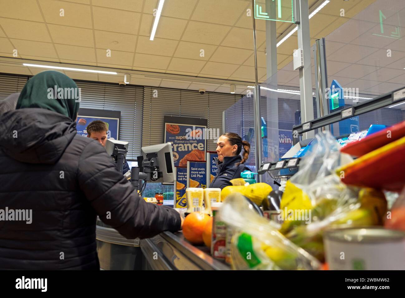 Young woman employee working on till food on checkout counter in Lidl