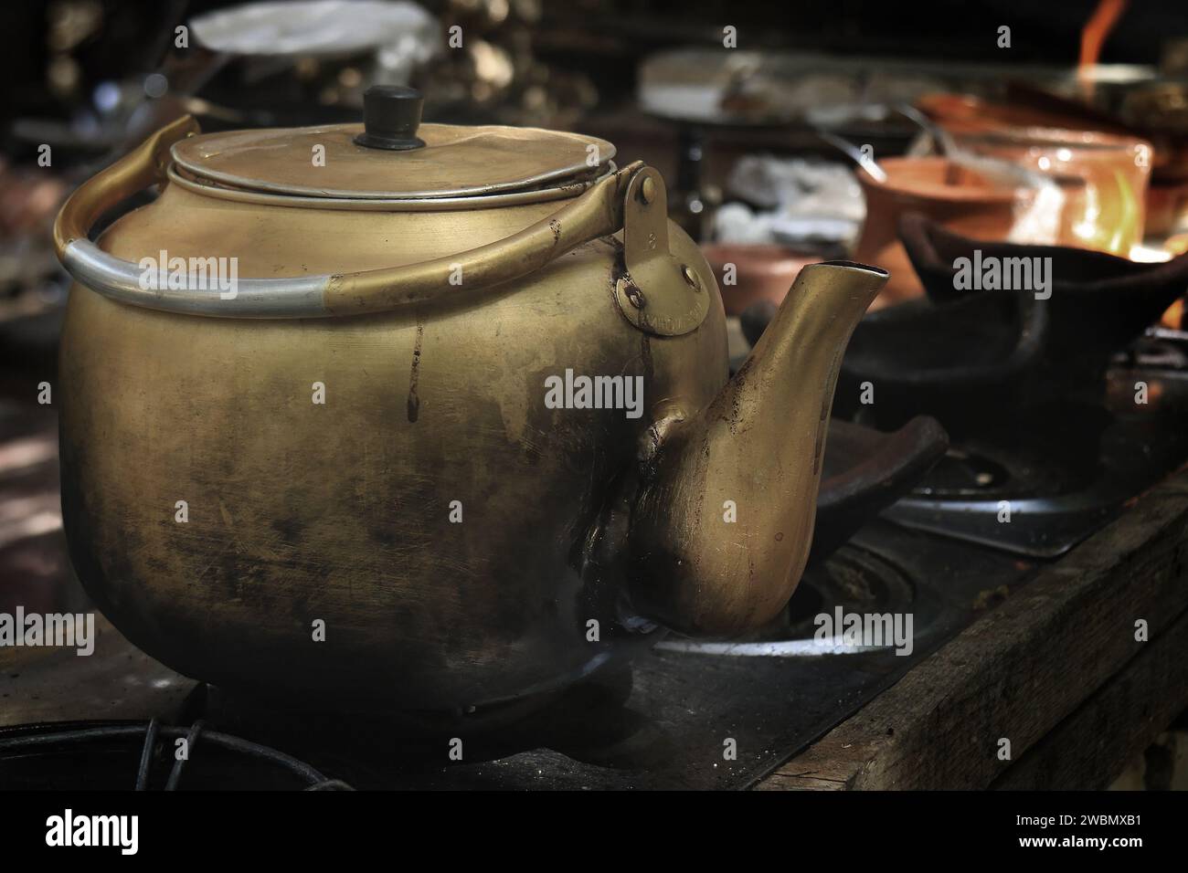 A brass coffee kettle brewing on a stove. Stock Photo