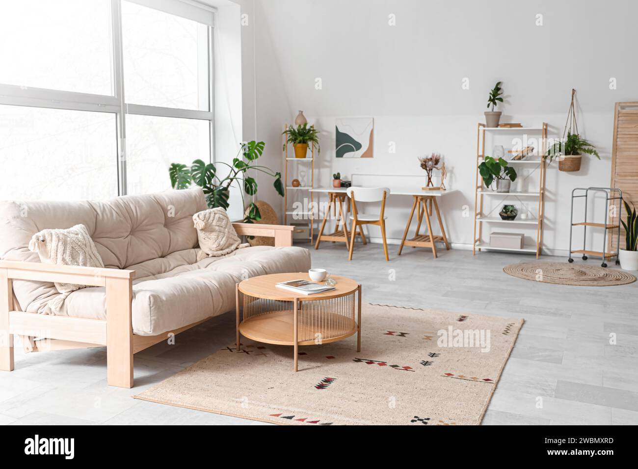 Interior of living room with sofa, plants and workplace Stock Photo - Alamy