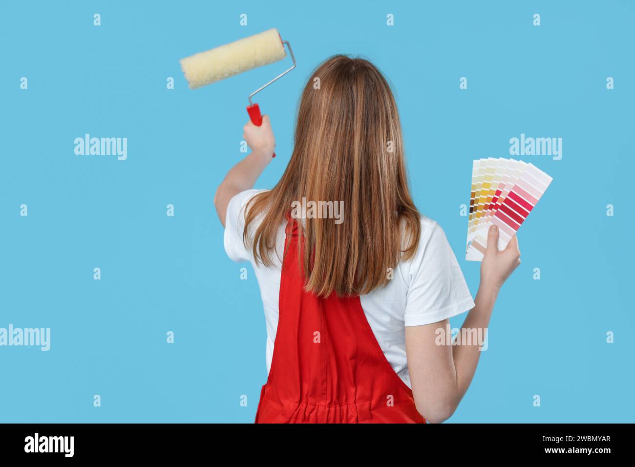 Female painter with color palettes and paint roller on blue background ...