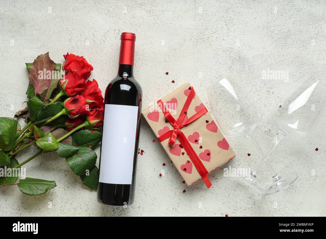 Bottle of wine with glasses, gift box and red roses on white background ...