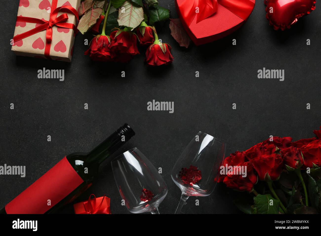 Bottle of wine with glasses, gift boxes and red roses on black ...