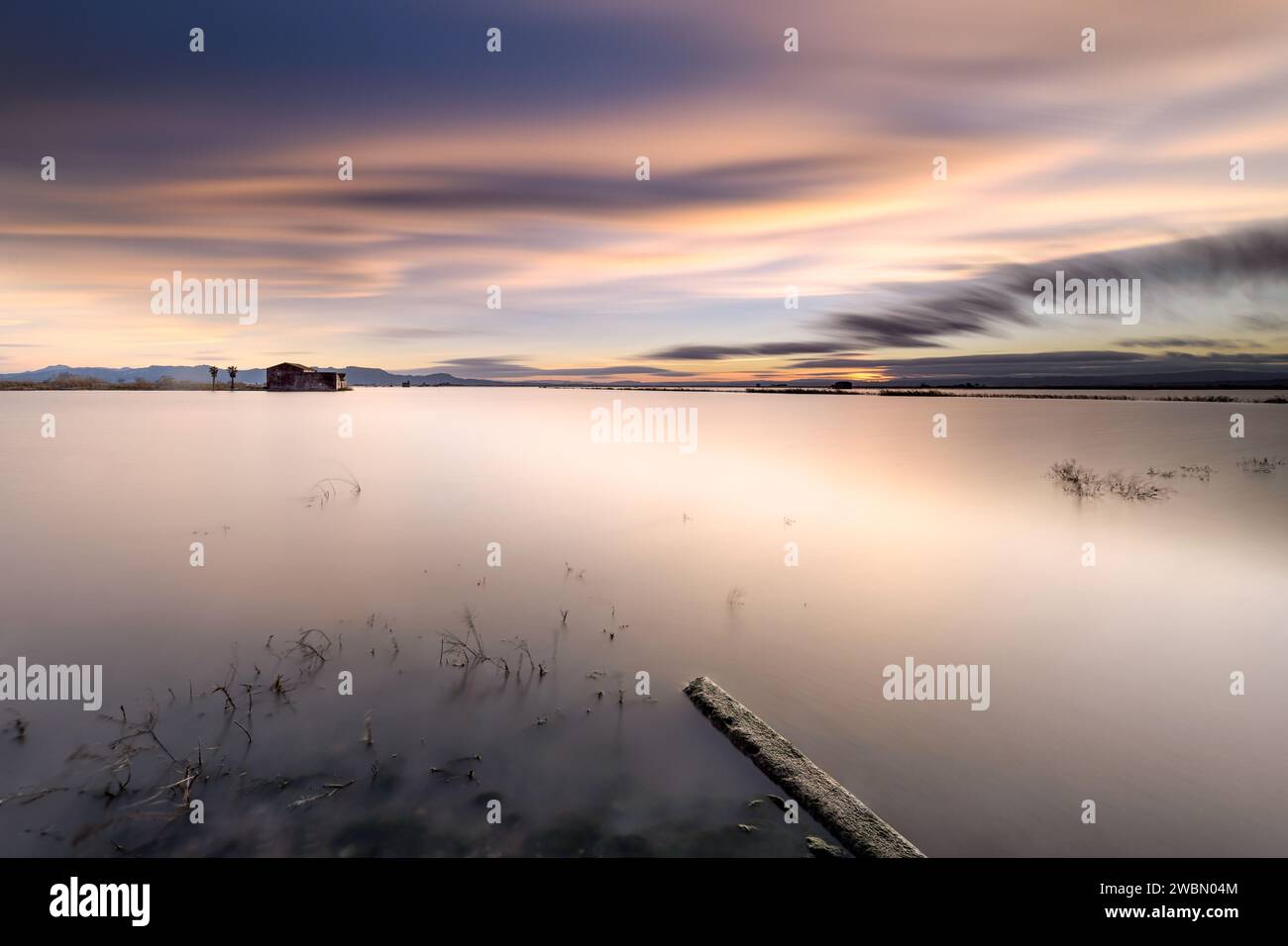 Long exposure with silky water to capture a beautiful sunset in the flooded rice fields with an idyllic landscape, Sueca, Valencia, Spain. Stock Photo