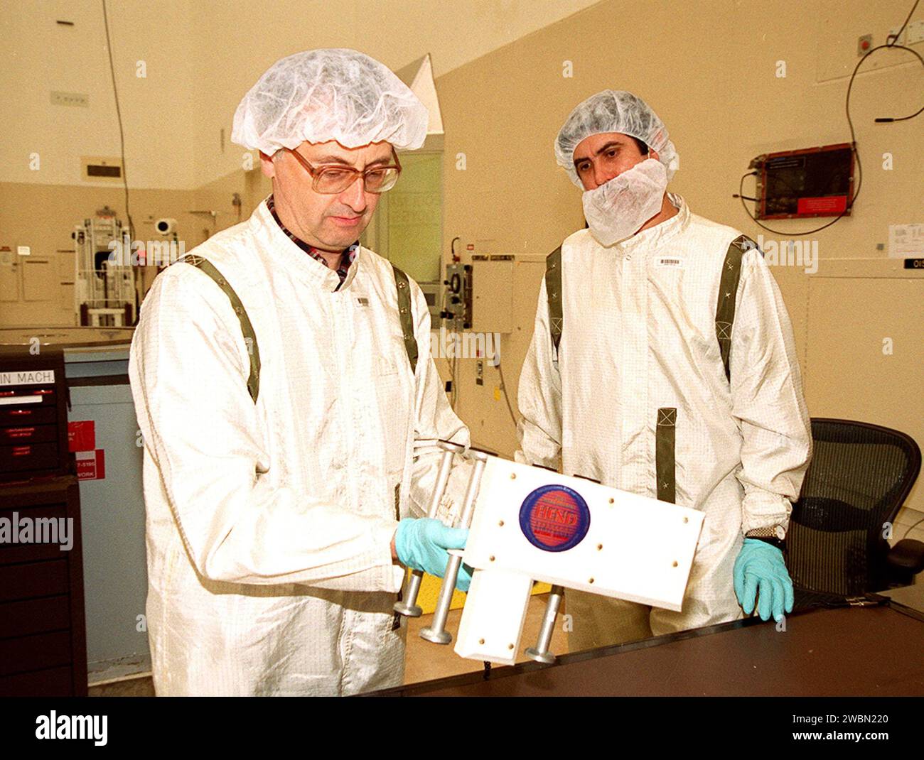 Two Russian scientists look over the High Energy Neutron Detector (HEND), part of the Gamma Ray Spectrometer (GRS), after its removal from the 2001 Mars Odyssey Orbiter. The HEND was built by Russia’s Space Research Institute (IKI). The GRS will achieve global mapping of the elemental composition of the surface and determine the abundance of hydrogen in the shallow subsurface. The orbiter will carry two other science instruments THEMIS and the Mars Radiation Environment Experiment (MARIE). THEMIS will map the mineralogy and morphology of the Martian surface using a high-resolution camera and a Stock Photo