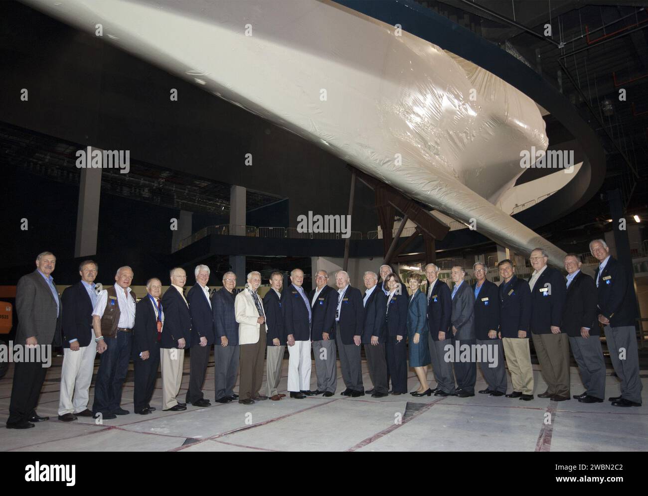 CAPE CANAVERAL, Fla. – At NASA’s Kennedy Space Center Visitor Complex in Florida, members of the U.S. Astronaut Hall of Fame are joined by Bill Moore, chief operating officer of the visitor complex pose under the space shuttle Atlantis in the facility where it will be displayed beginning June 29. The shuttle is currently protected by plastic wrap as constitution contuse. Pictured, left to right are, Curt Brown, Robert, 'Hoot' Gibson, Buzz Aldrin, Joe Allen, Rick Hauck, Steven Hawley, Fred Haise, Owen Garriott, Brewster Shaw. Jack Lousma, Dan Brandenstein, Vance Brand, Loren Shriver, Moore, Bon Stock Photo