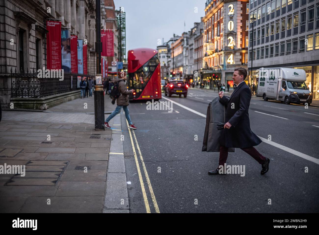 Businessman holding a suit carrying bag across Piccadilly in the heart of London's Mayfair district, London, UK Stock Photo