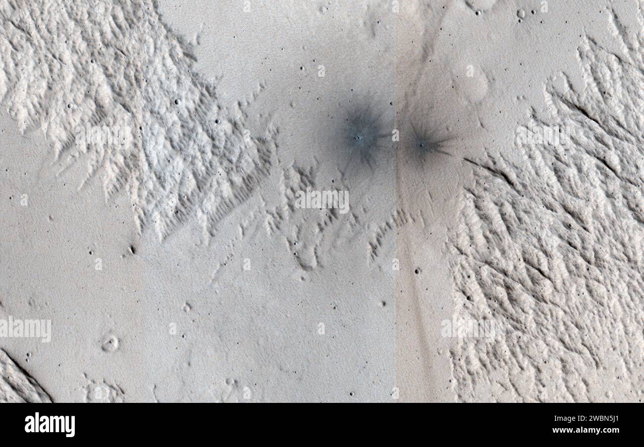 This image shows terrain near Mangala Valles. At the bottom of the image are two black spots that are recent impact craters. The black spots form because the craters exposed cleaner materials in the subsurface beneath the bright, dusty surface. Our image is also interesting because the surface has a criss-cross pattern formed by wind activity. Bright ripples that are oriented from the upper right to the lower left are perpendicular to the wind flow. In contrast, outcrops that have been eroded by the wind are oriented perpendicular to the ripples to produce the criss-cross pattern we now observ Stock Photo