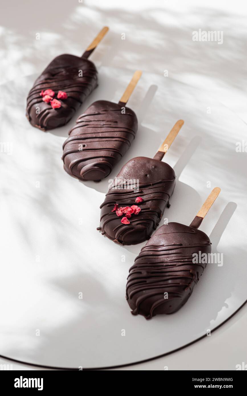 Delicious chocolate covered ice cream on stick against white background