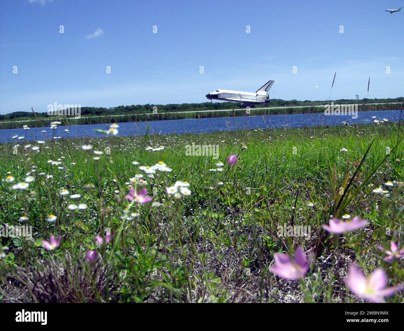 KENNEDY SPACE CENTER, FLA. - A field of wild flowers greets Atlantis as it touches down on runway 33 at KSC, the drag chute just deployed. The landing completes the 10-day, 19-hour, 4.5-million mile mission STS-110 to the International Space Station. In the upper right corner is the chase plane following Atlantis' path. The orbiter carries the returning crew Commander Michael Bloomfield, Pilot Stephen Frick and Mission Specialists Jerry Ross, Steven Smith, Ellen Ochoa, Lee Morin and Rex Walheim. Main gear touchdown was 12 26 57 p.m. EDT, nose gear touchdown was 12 27 09 p.m. and wheel stop was Stock Photo