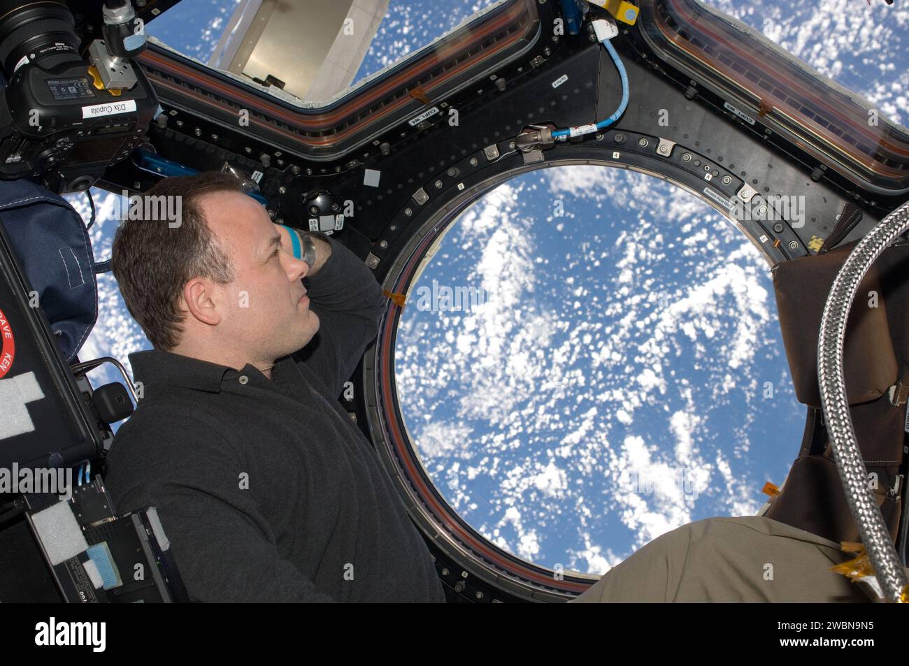 ISS028-E-048088 (11 Sept. 2011) --- NASA astronaut Ron Garan, Expedition 28 flight engineer, views a point on Earth through one of the windows in the Cupola of the International Space Station. Stock Photo