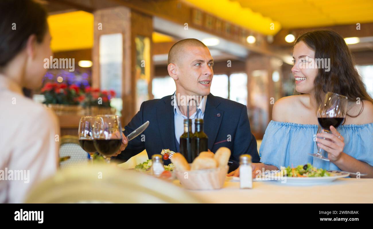 Two cheerful couples having dinner and nice talking Stock Photo