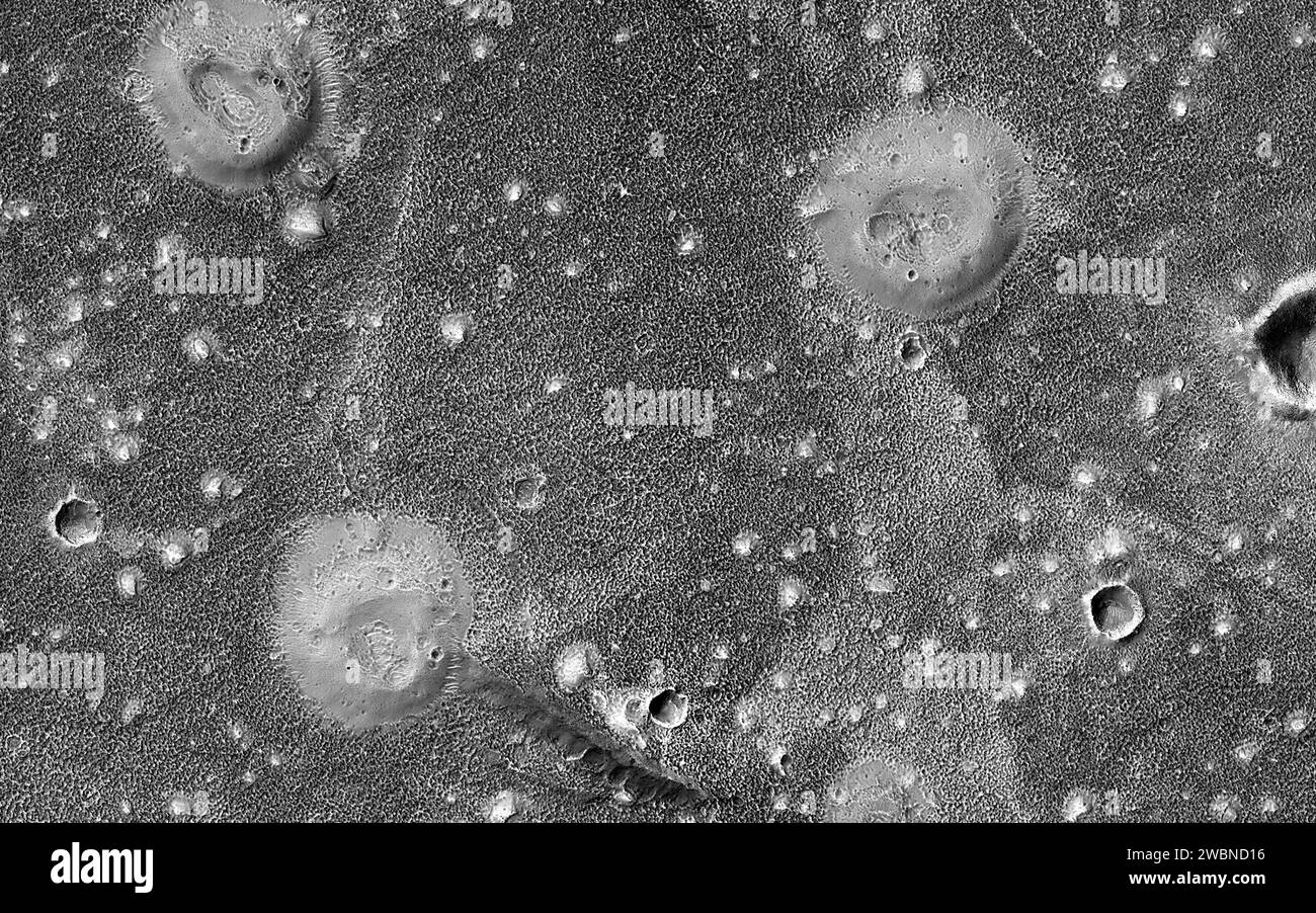 The northern lowlands of Mars in this location are stippled with mounds, such as those visible throughout this image. These lighter-toned circular mounds with bowl-shaped depressions are easy to spot against the darker-toned floor. Scientists think these landforms are similar to mud volcanoes that are also found here on Earth. Mud volcanoes form as gas and liquid-rich sediment interacts underground. Over time, this slurry of mud is brought to the surface and forms a rounded mound. Scientists are interested in studying mud volcanoes on Mars because the material forming the mound has the potenti Stock Photo
